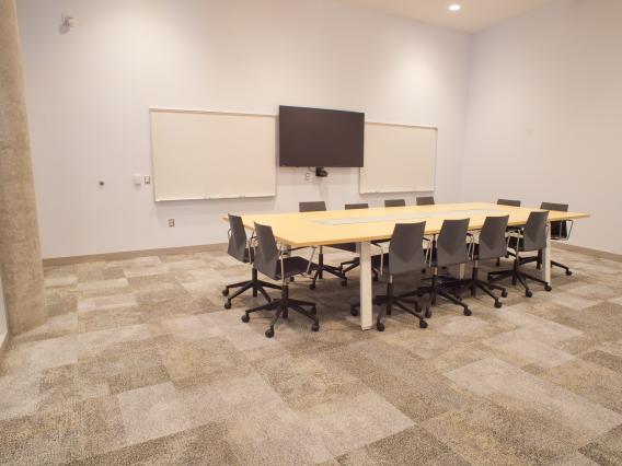Photo of room S120A in ENR2 with a table, chairs surrounding it, and a monitor mounted to the wall.
