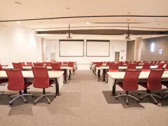 Photo of room S107 in ENR2 with multiple tables and chairs as well as projector screens mounted on the wall.