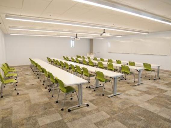 Photo of room S210 in ENR2 with multiple tables and chairs as well as projector screens mounted on the wall.