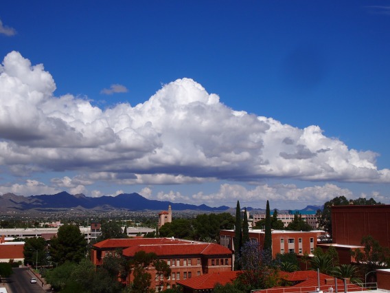 Large clouds in an otherwise clear blue sky above the University of Arizona