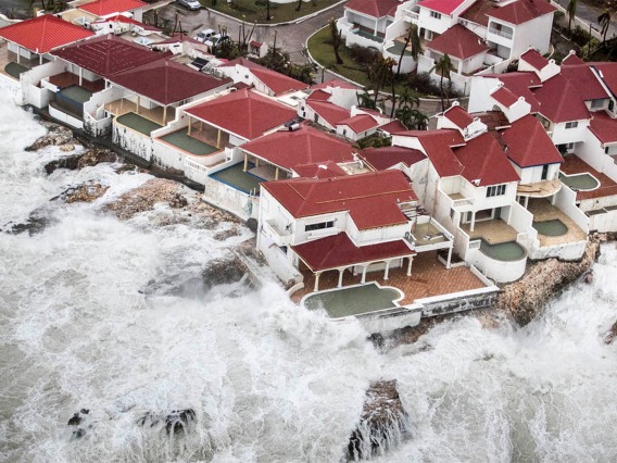 Waves overtake houses with swimming pools.