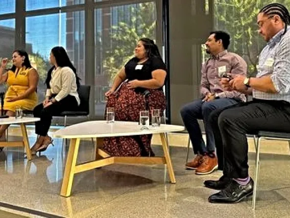 A panel of speakers on a platform in front of large windows at the September 18 Arizona Town Hall.