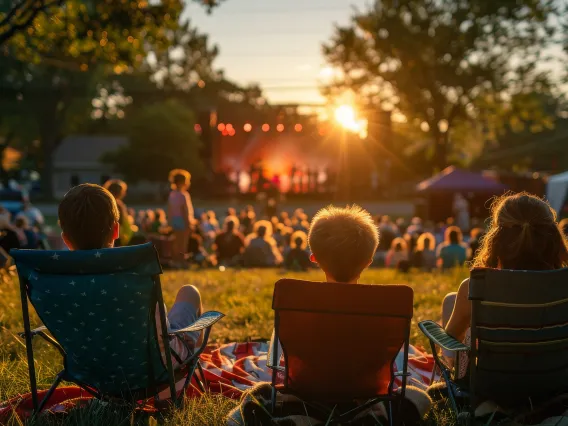 People lounge on a lawn at an outdoor concert.