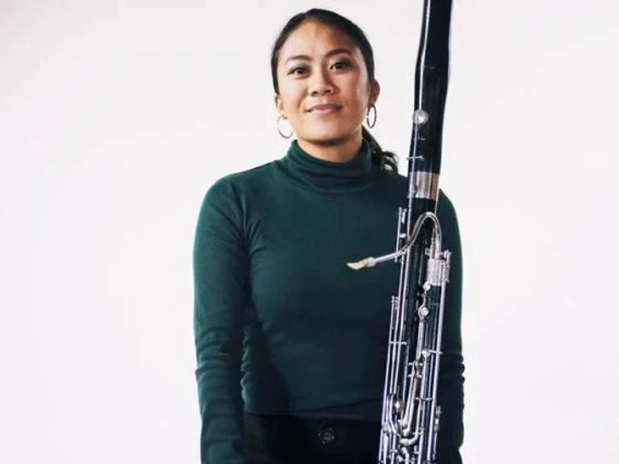 Marissa Olegario holding bassoon in front of a white background.