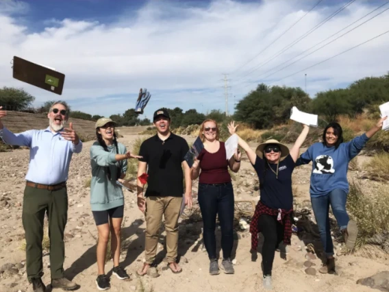 A group of people smiling while holding notebooks in the air.