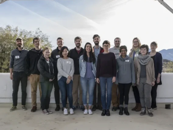 A group of people stand smiling together outdoors.