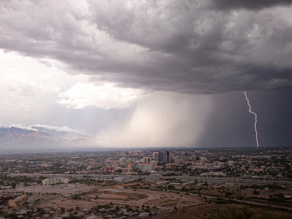 A raincloud brings rain and lightning over the desert landscape.