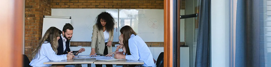 a group of three people looking together at a laptop on table.