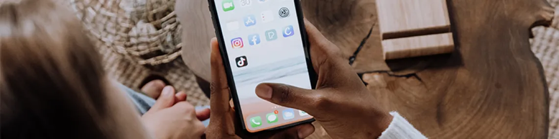 a smart phone held by a person. the screen is on the home page, showing some applications.