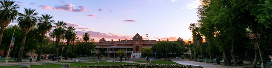 the front of the Old Main building during sunset. the sunlight is casting a pink hue visible along the top of the building.
