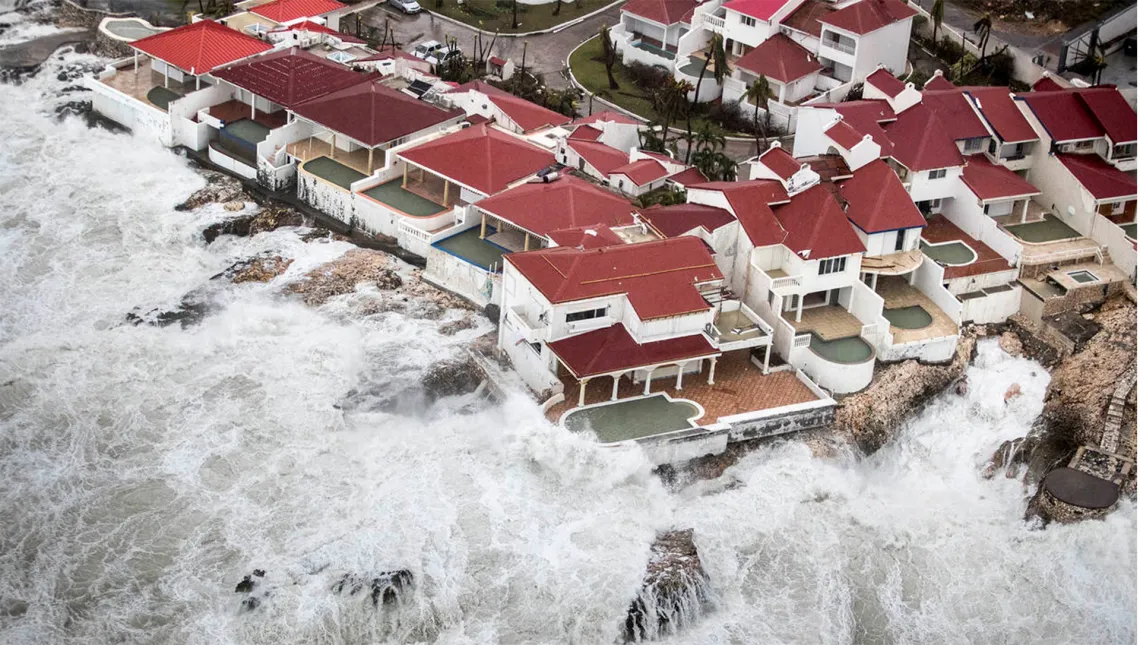 Waves overtake houses with swimming pools.