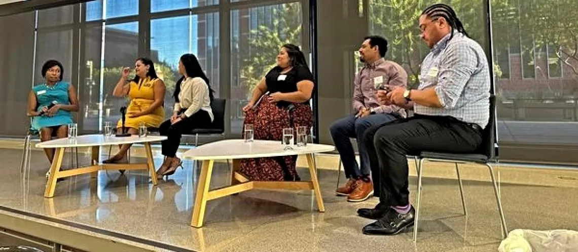 A panel of speakers on a platform in front of large windows at the September 18 Arizona Town Hall.