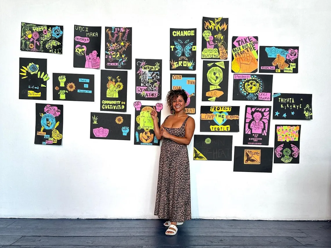 A woman stands before a wall of colorful posters.