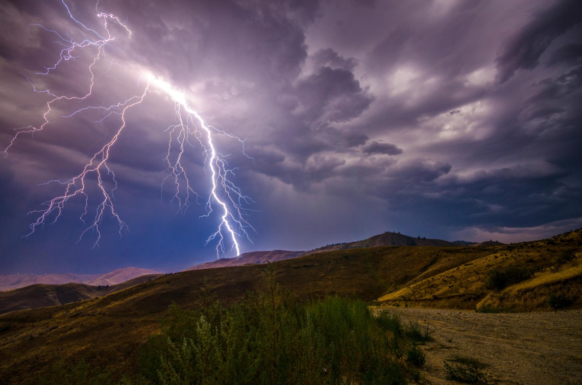 Lightning over a hillside at night.
