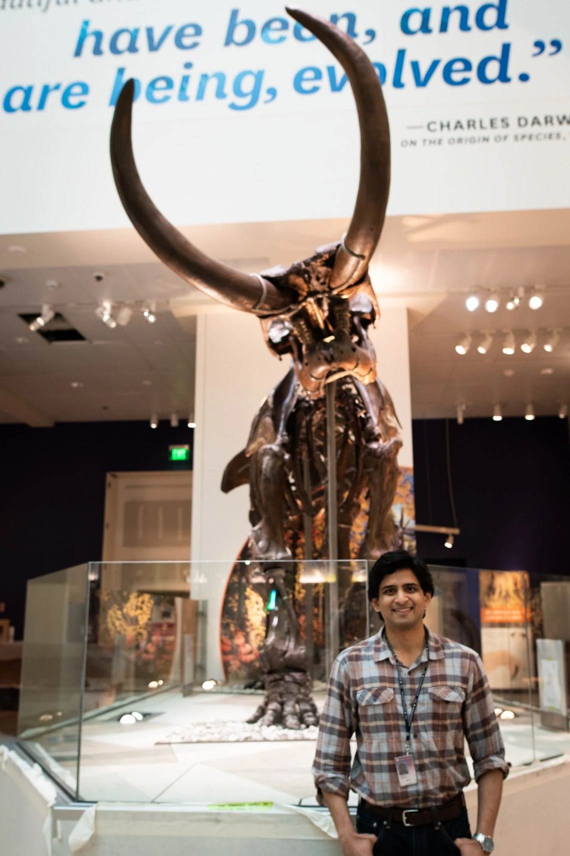 Photo of Dr. Advait Jukar standing in front of Mammal Fossil in a Museum