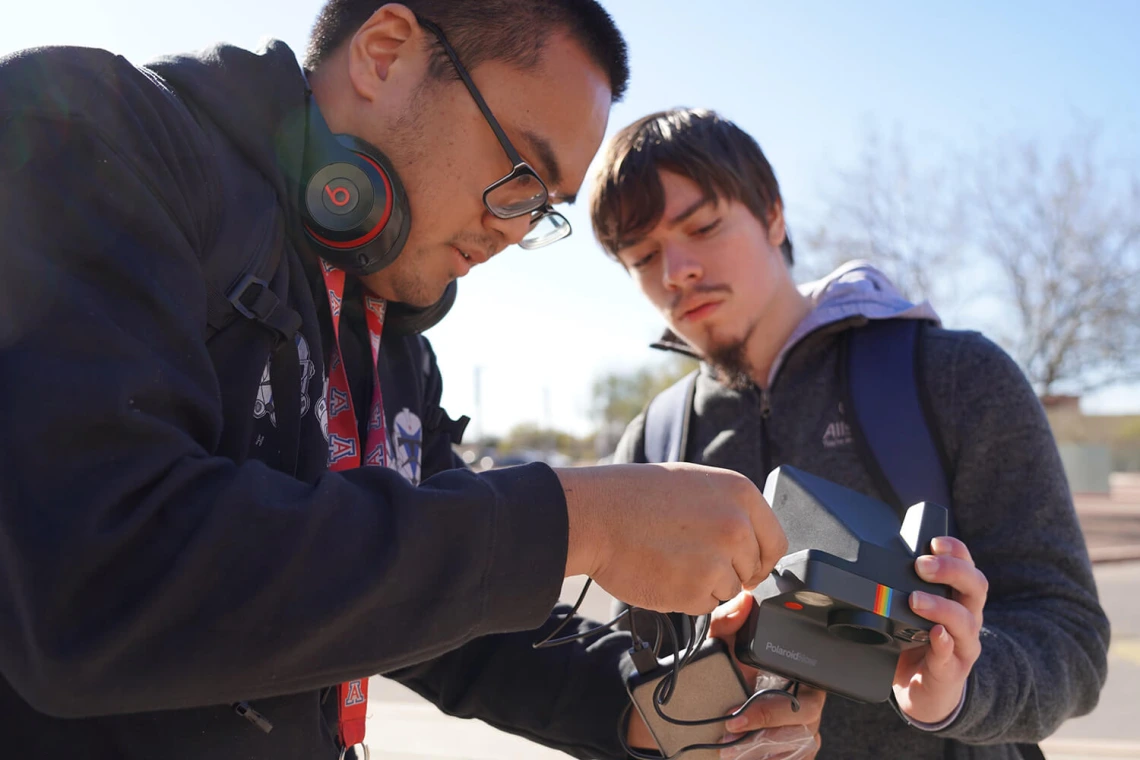 Two people work together outdoors.