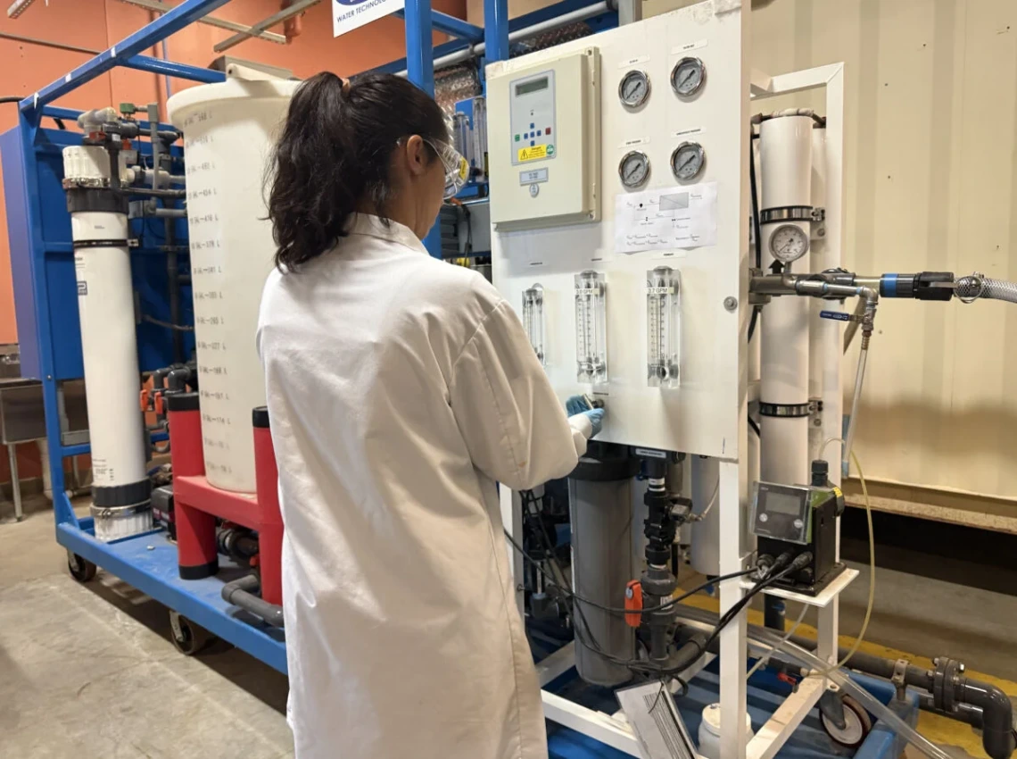 A researcher in a white lab coat prepares a water ultrafiltration machine.
