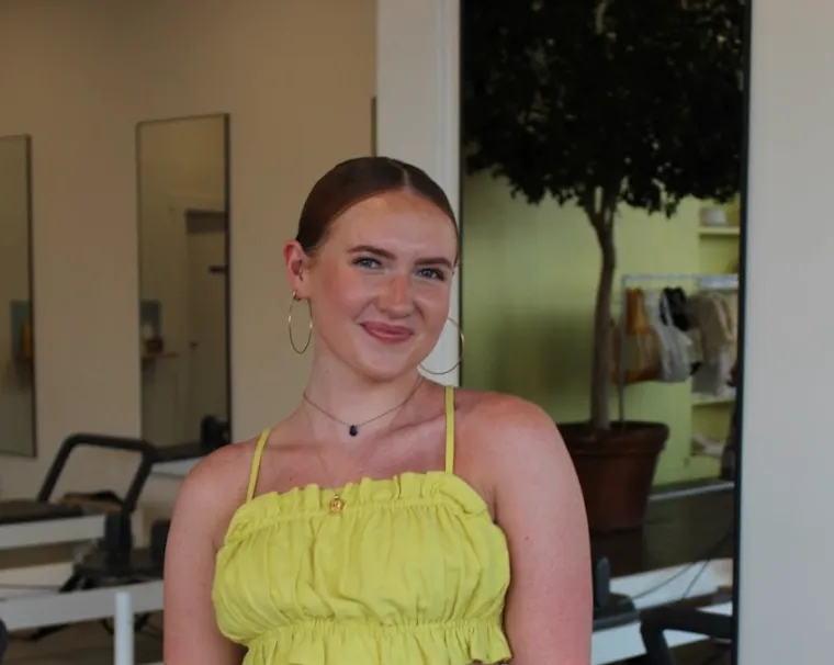 Audrey Lockman: photo of woman in a yellow top, brown hair pulled back, and hoop earrings smiling at camera