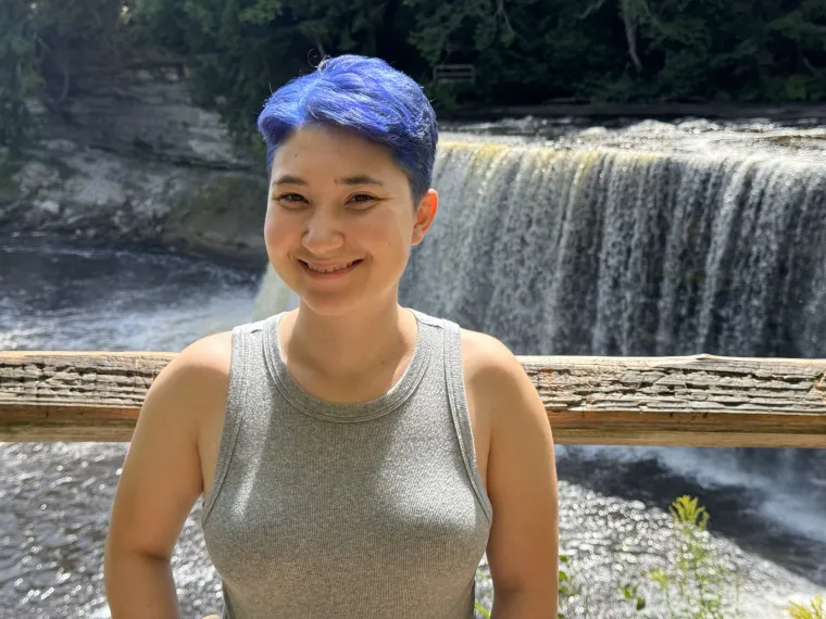 Zoe Johnson: Woman with short, blue hair standing in front of a waterfall