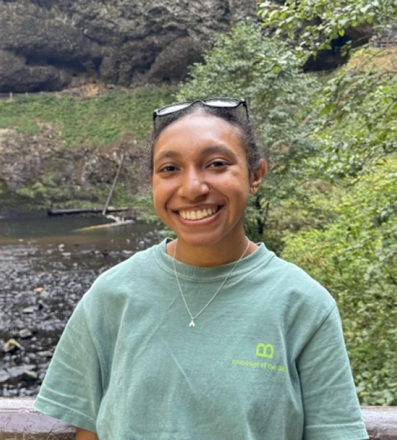 Headshot of Christien Stevany in front of greenery and natural water