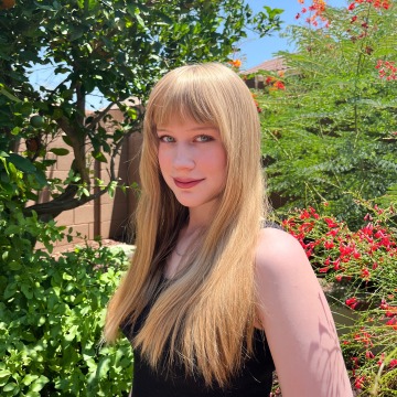 A woman with long blond hair standing in a garden