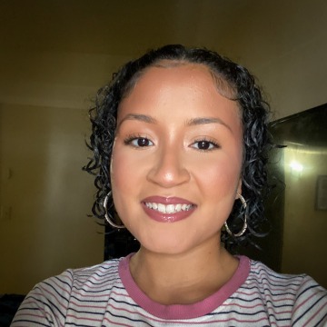 A woman smiling in a striped shirt and hoop earrings