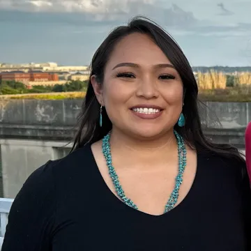 Woman with black shirt and blue jewelry smiling 