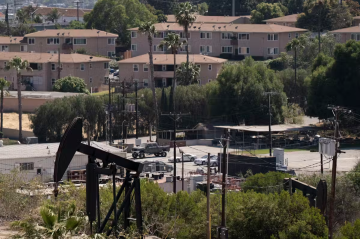 An oil well with houses in the background.