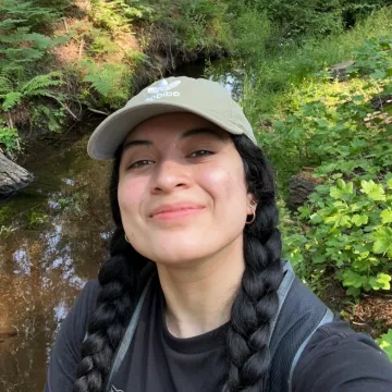 Smiling student wearing hat in front of pond