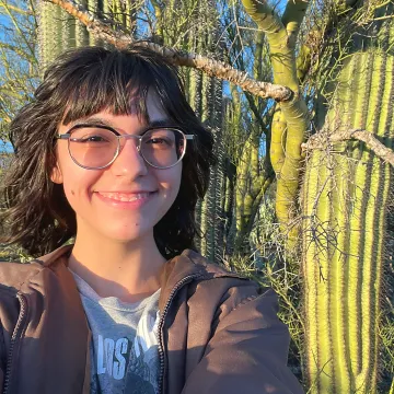 Smiling student wearing glasses in front of cactus