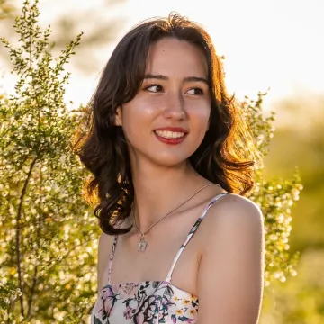 Student smiling and looking away with plant behind