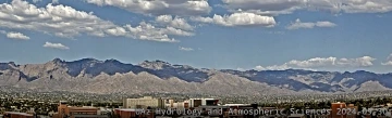 An aerial image of clouds over a city with mountains in the background.