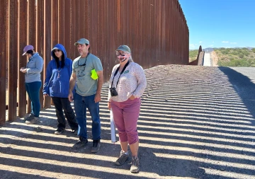 People stand at the Arizona - Mexico boarder wall.