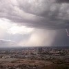 A raincloud brings rain and lightning over the desert landscape.