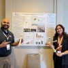 Two students standing in front of a research poster holding research instruments in their hands.