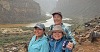 Three women stand together in the Grand Canyon with the Colorado River behind them.