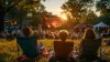 People lounge on a lawn at an outdoor concert.