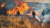 Firefighters approach a grass fire.